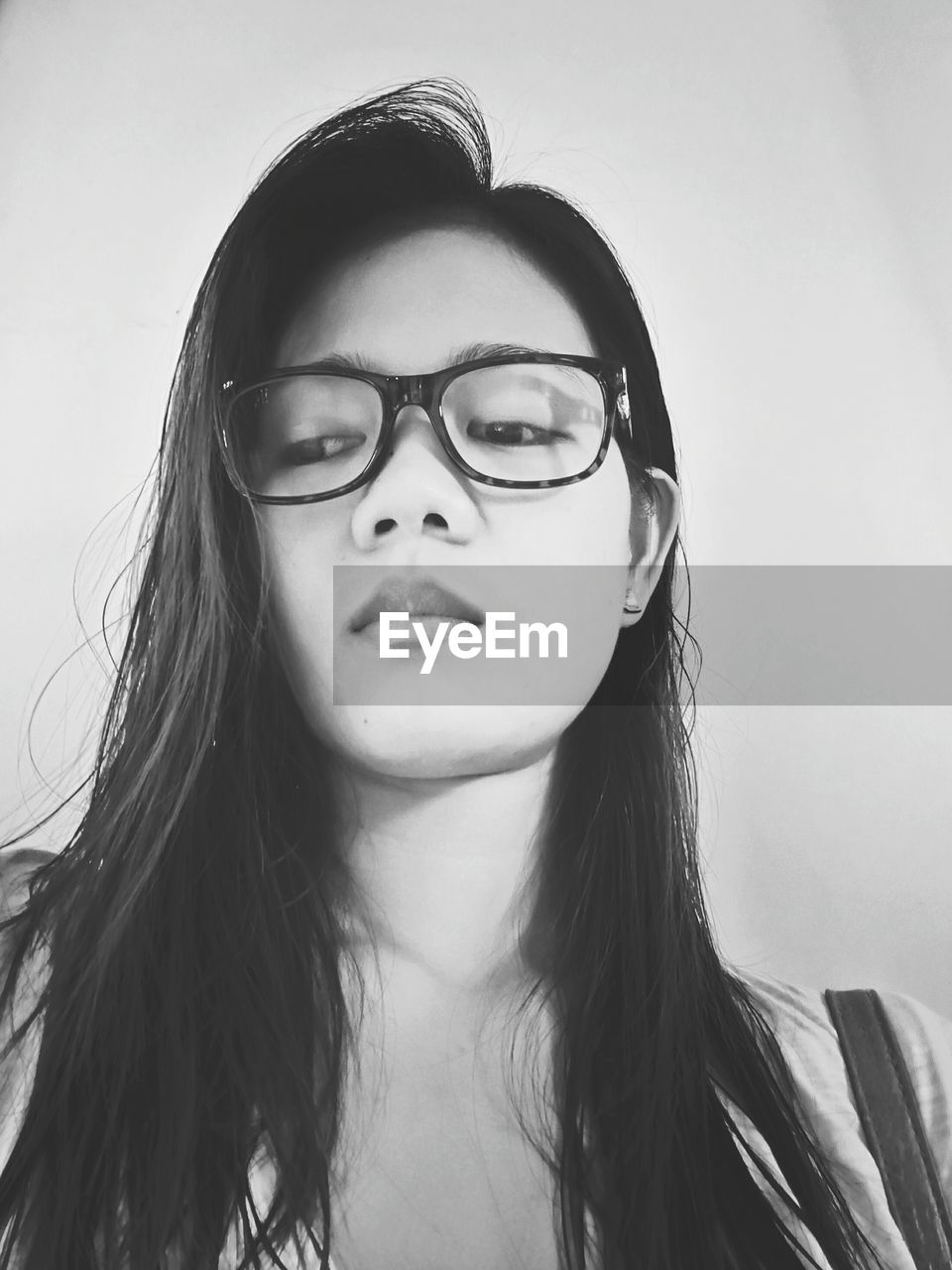 Low angle view of beautiful woman wearing eyeglasses against white wall
