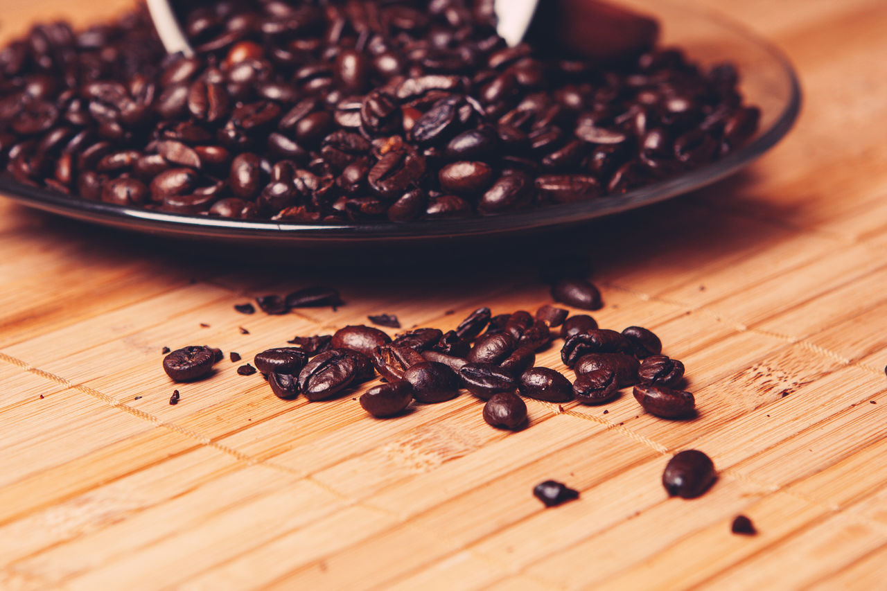 CLOSE-UP OF COFFEE BEANS ON WOODEN TABLE