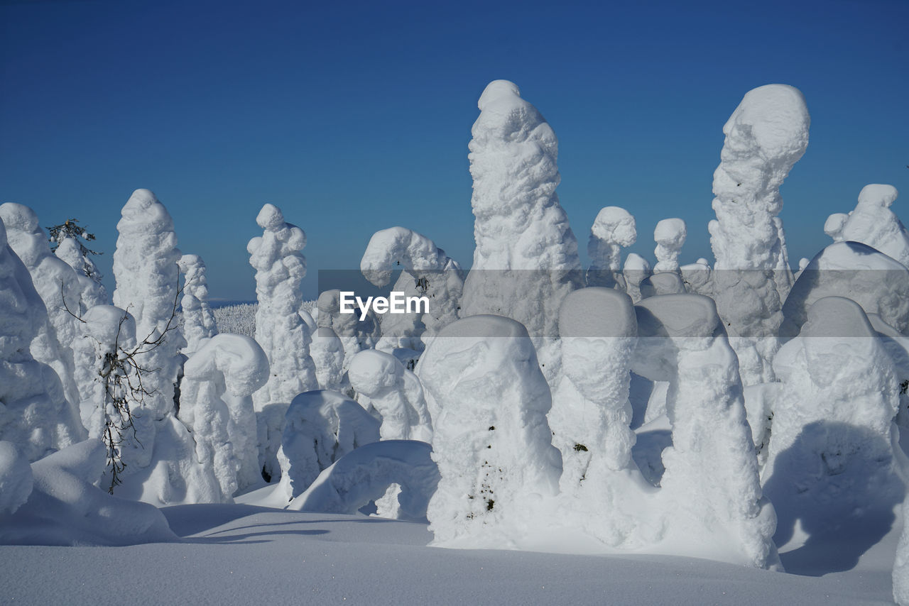 Snow covered landscape against clear blue sky