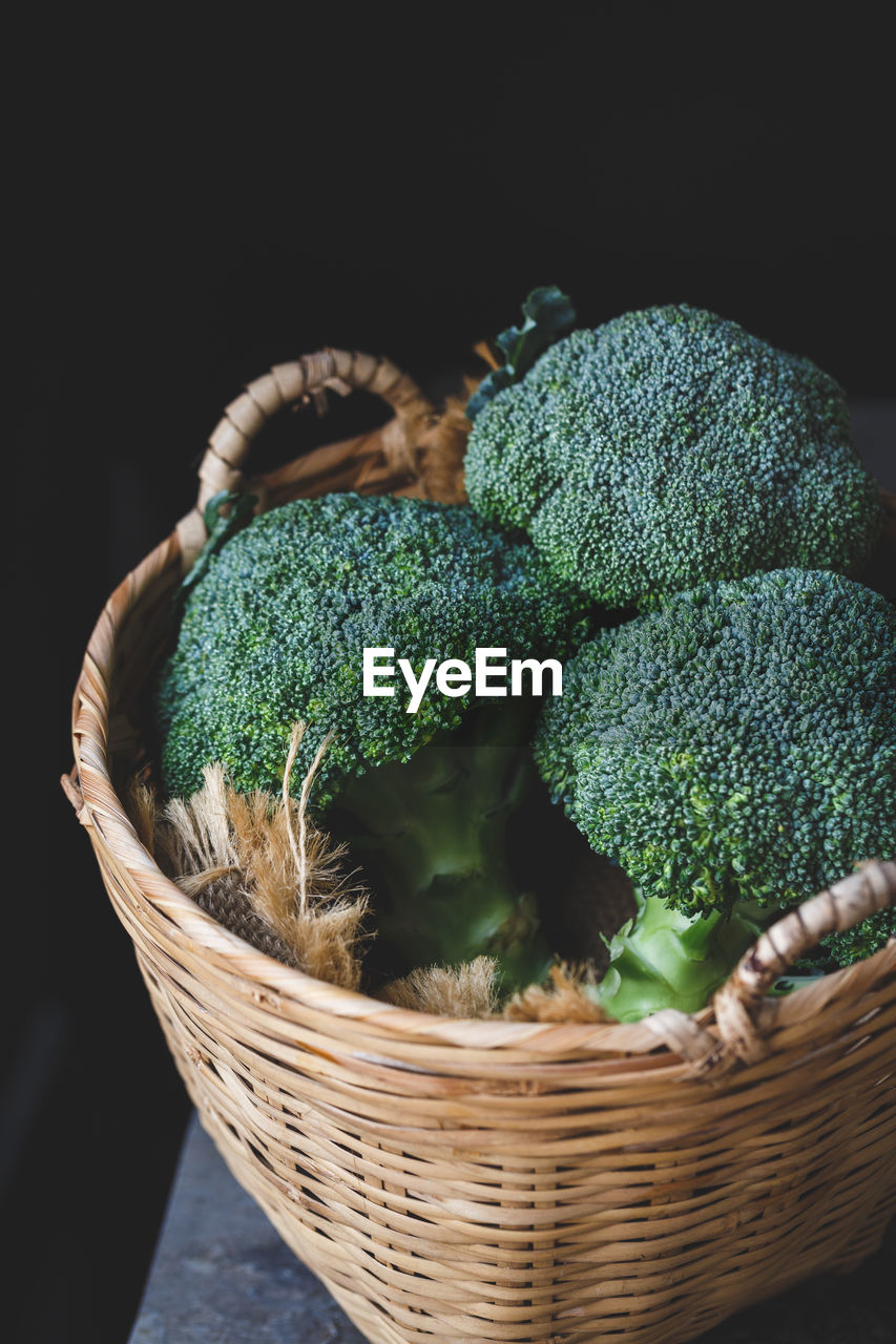 Close-up of broccolis in basket against black background