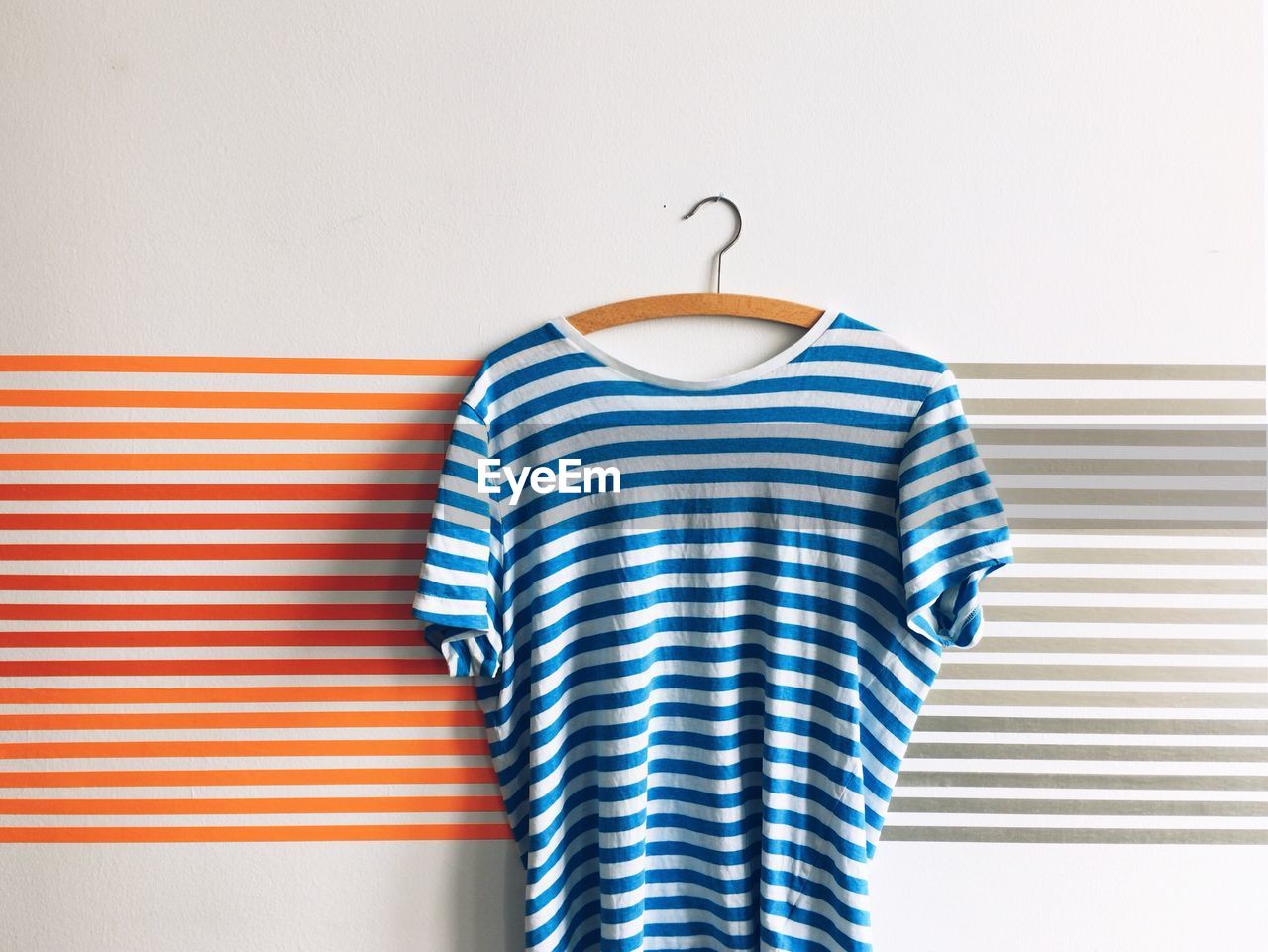 Striped t-shirt hanging on coathanger against patterned wall