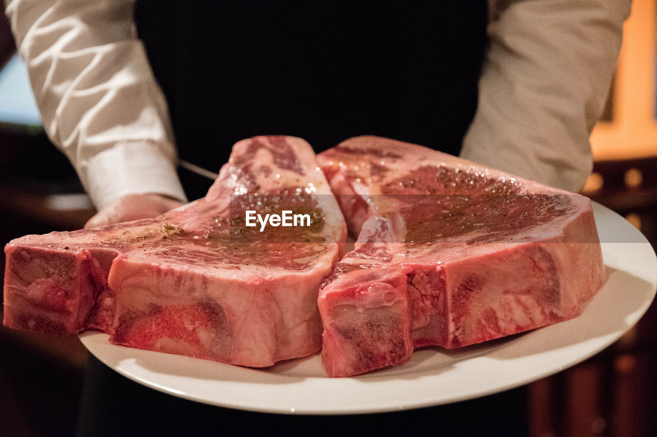 Midsection of man with meat on plate