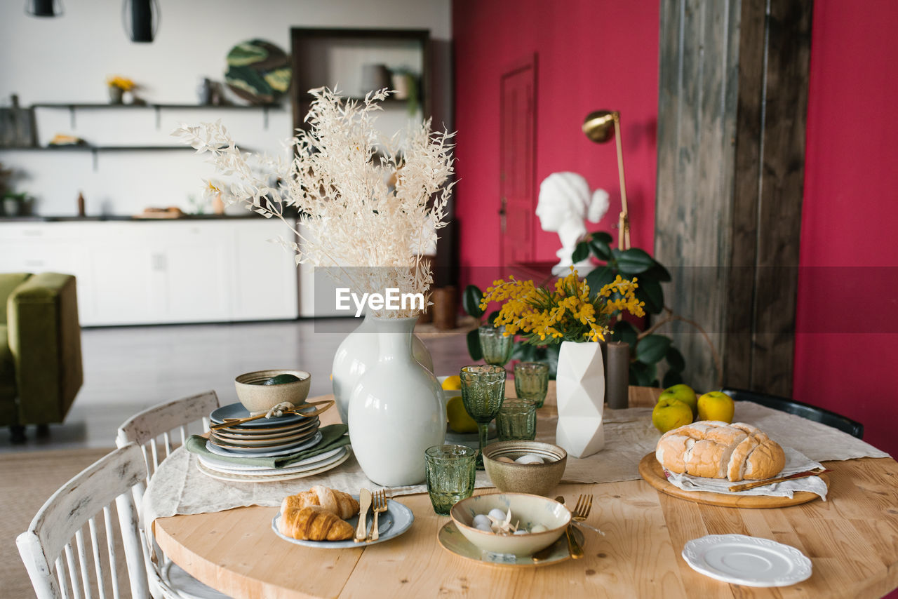 Festive easter table with mimosa flowers in a vase and traditional food, eggs. the interior 