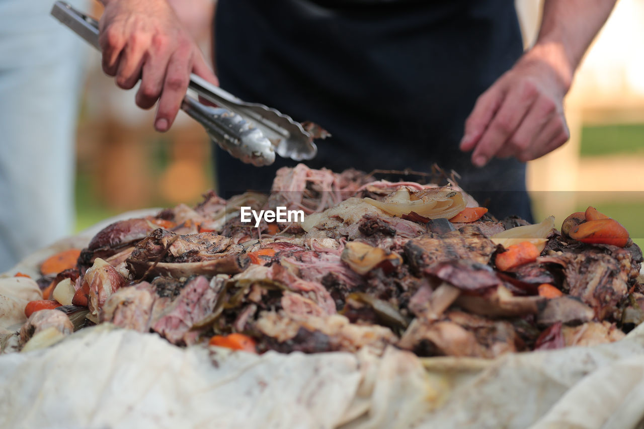 Midsection of man with serving tongs preparing food