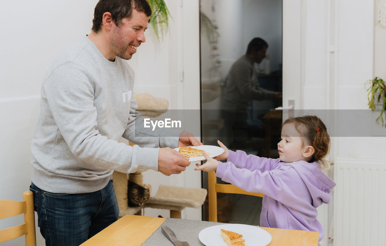 A little girl serves a royal galette to a guy.