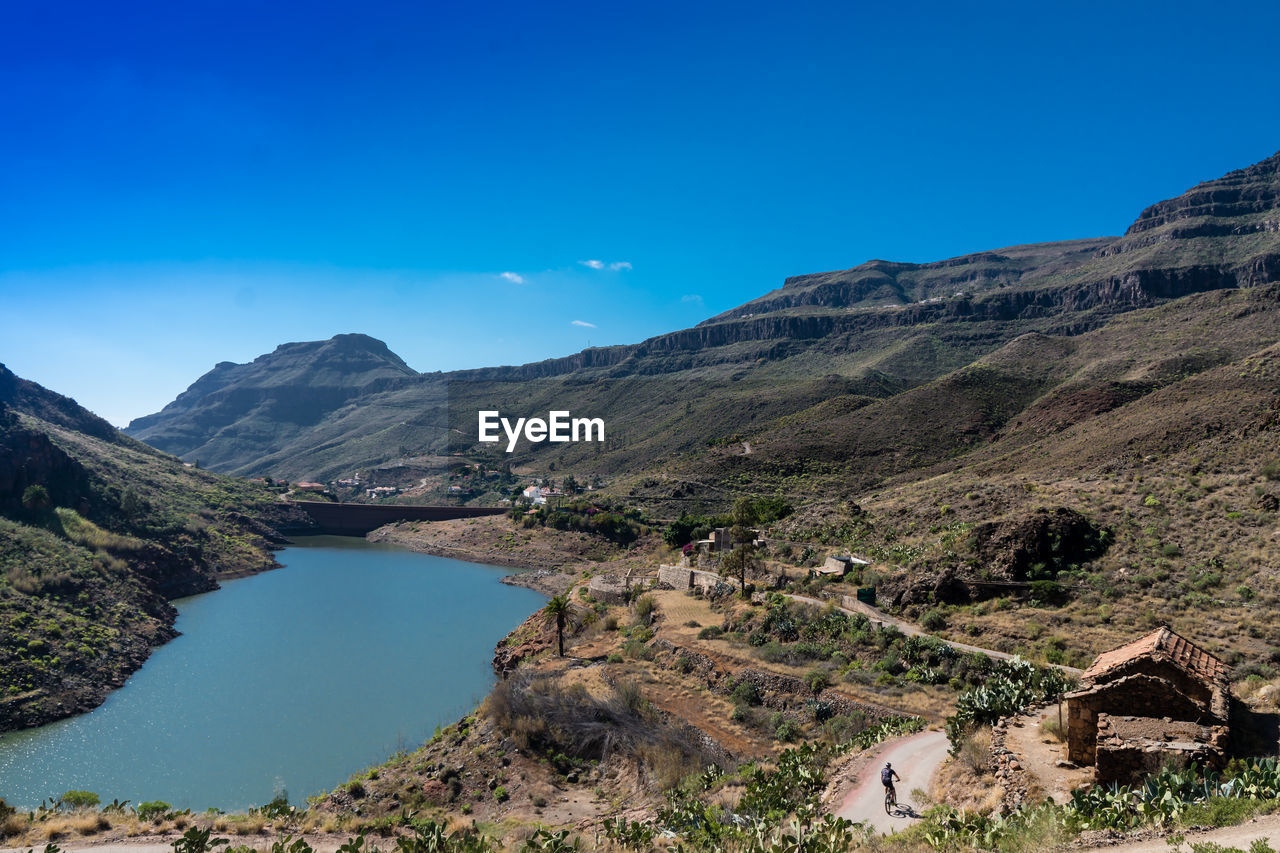 Scenic view of river and mountains against blue sky