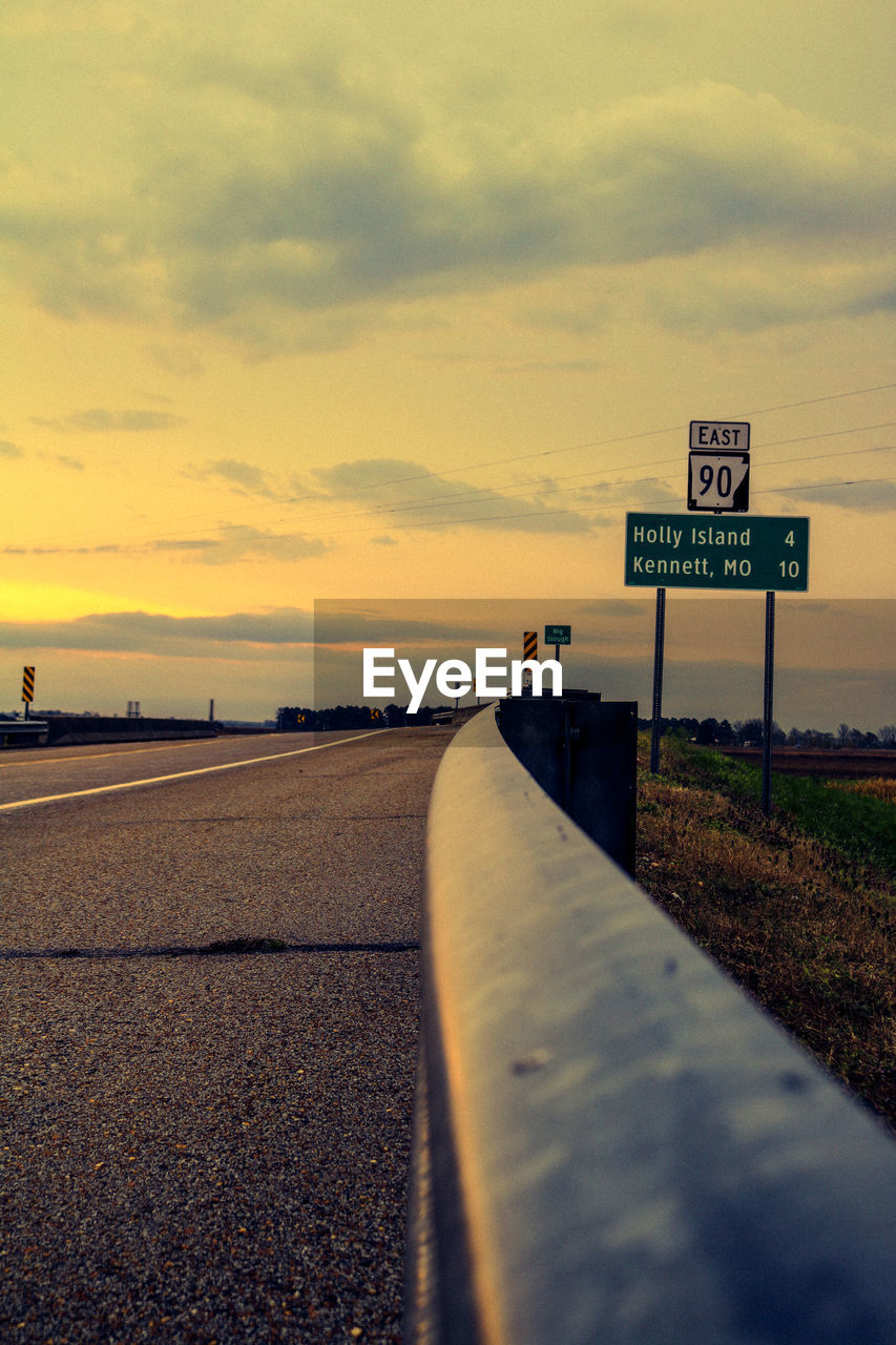 Road sign against sky during sunset