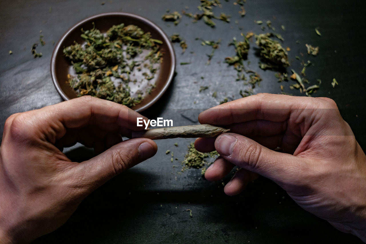 Cropped hands of man holding marijuana joint