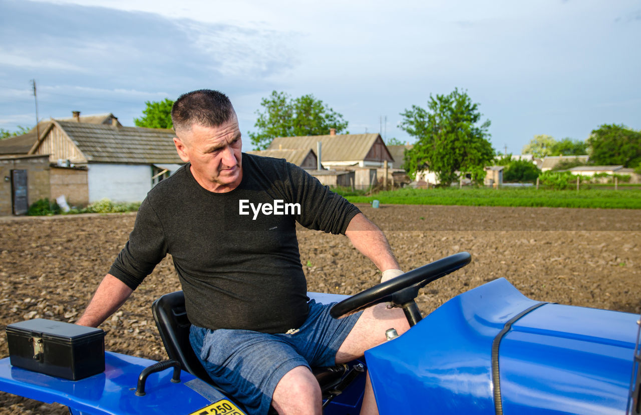 Kherson oblast, ukraine - may 29, 2021. an elderly farmer sits and drives a tractor. 