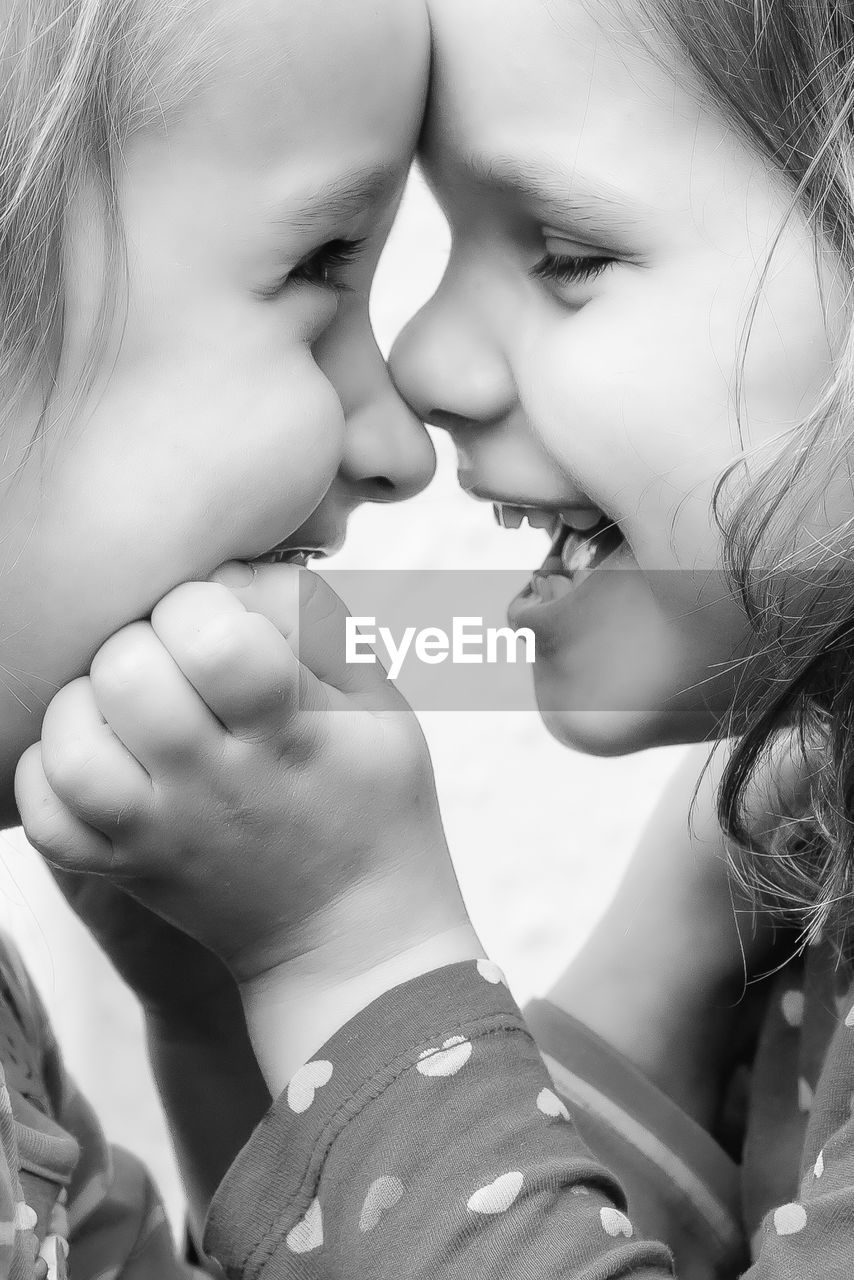 Close-up of cheerful sisters playing face to face