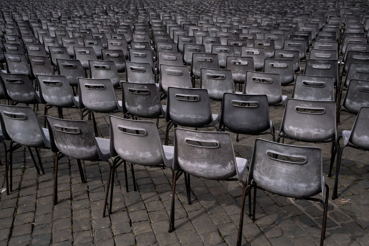 seat, chair, in a row, empty, side by side, arrangement, no people, repetition, absence, order, large group of objects, furniture, high angle view, day, monochrome