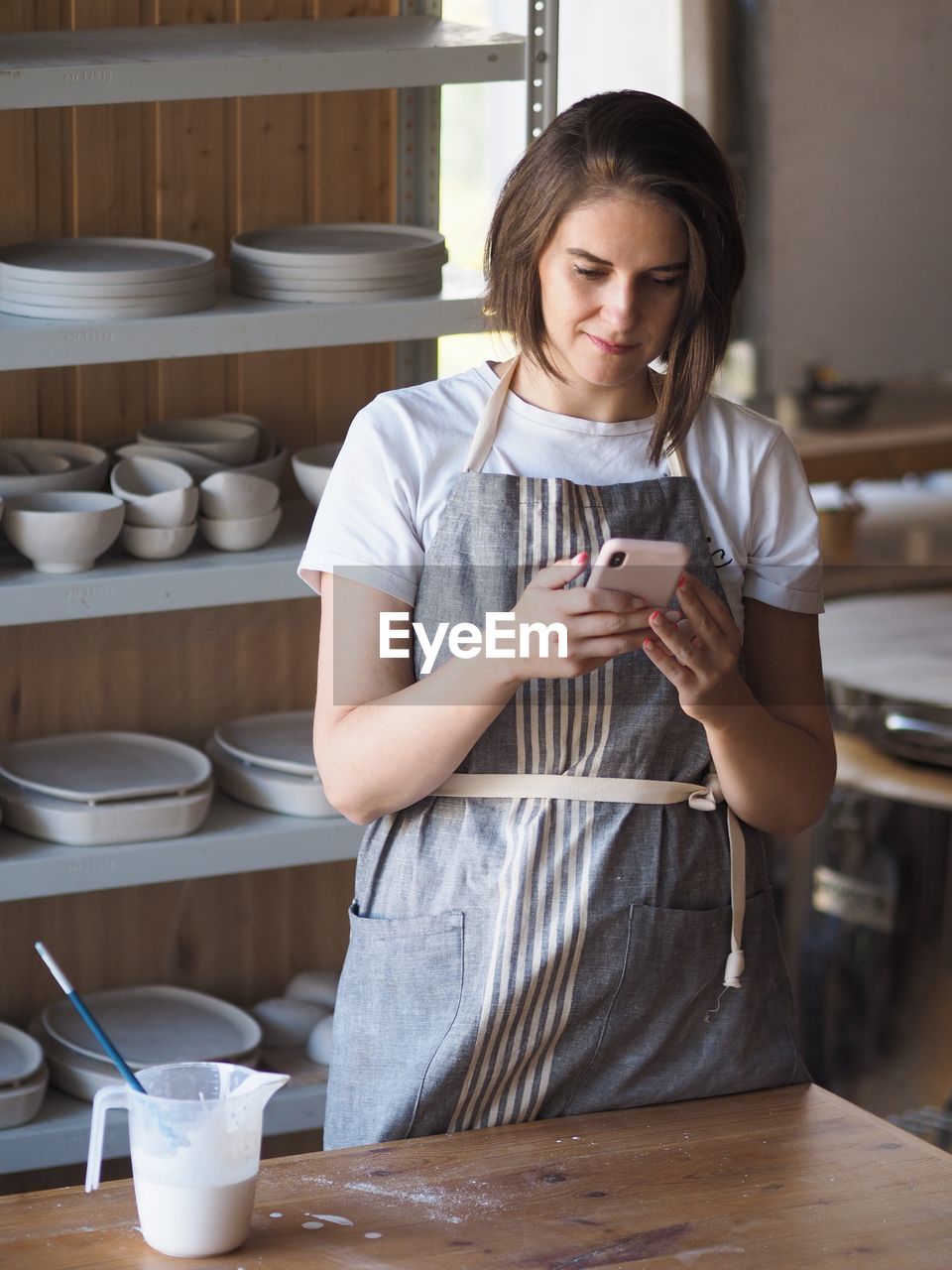 Smiling woman using mobile phone at kitchen