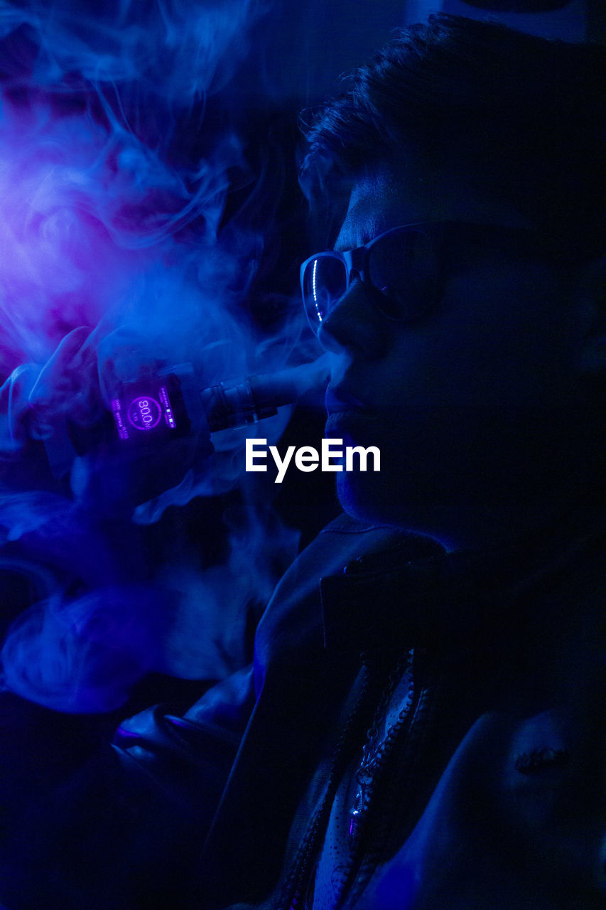 PORTRAIT OF MAN SMOKING AT NIGHT