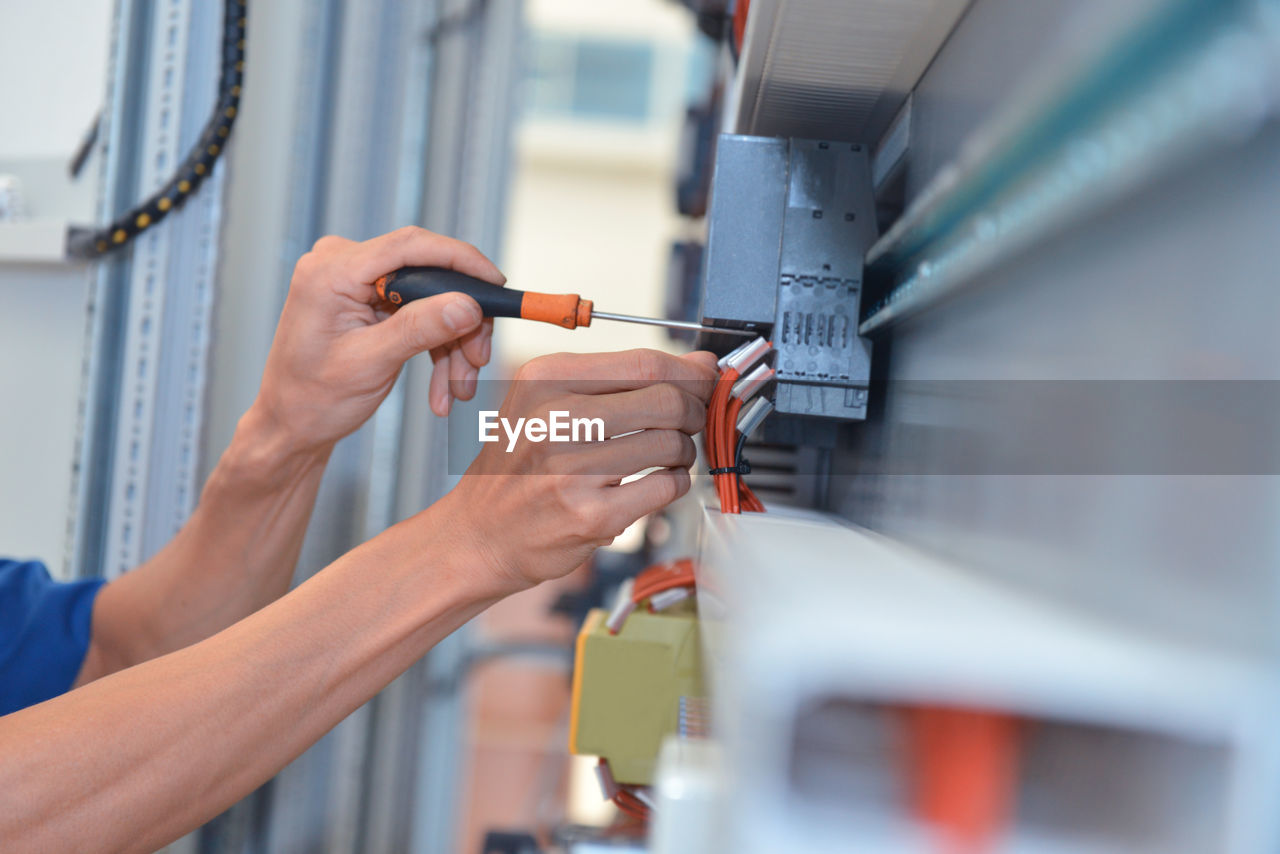 Cropped hands of electrician adjusting cables