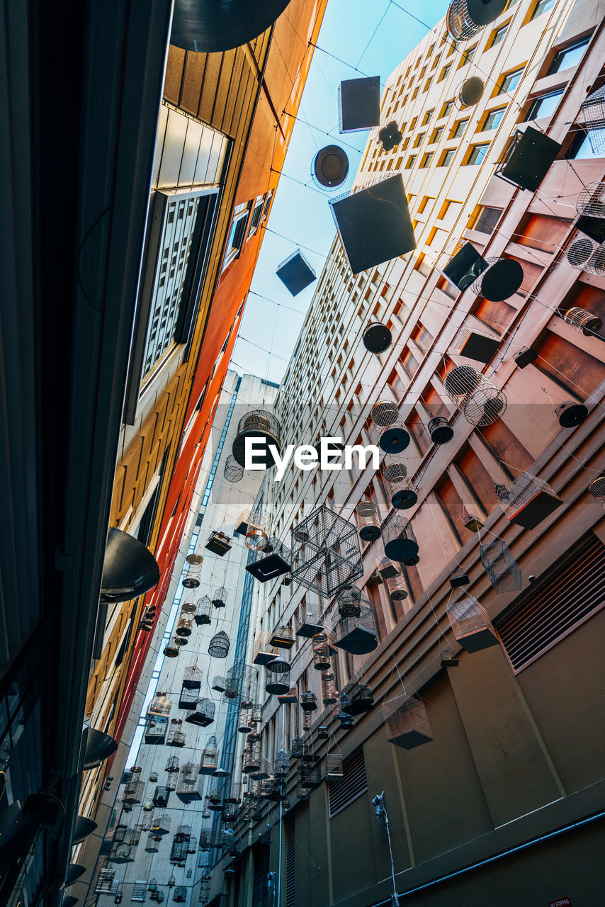 Low angle view of birdcages hanging amidst buildings in city