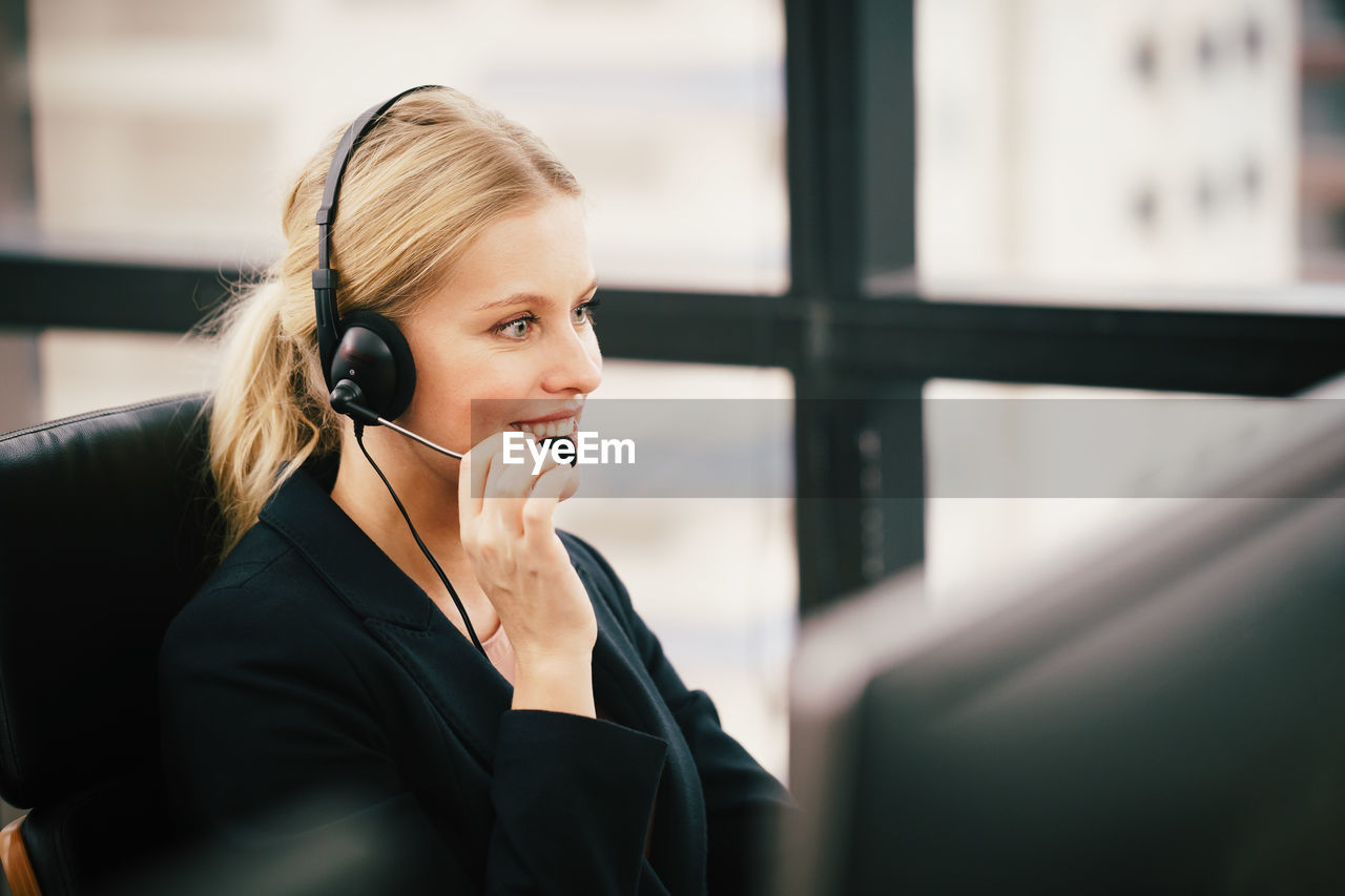 Female customer service representative talking on headset while sitting in office