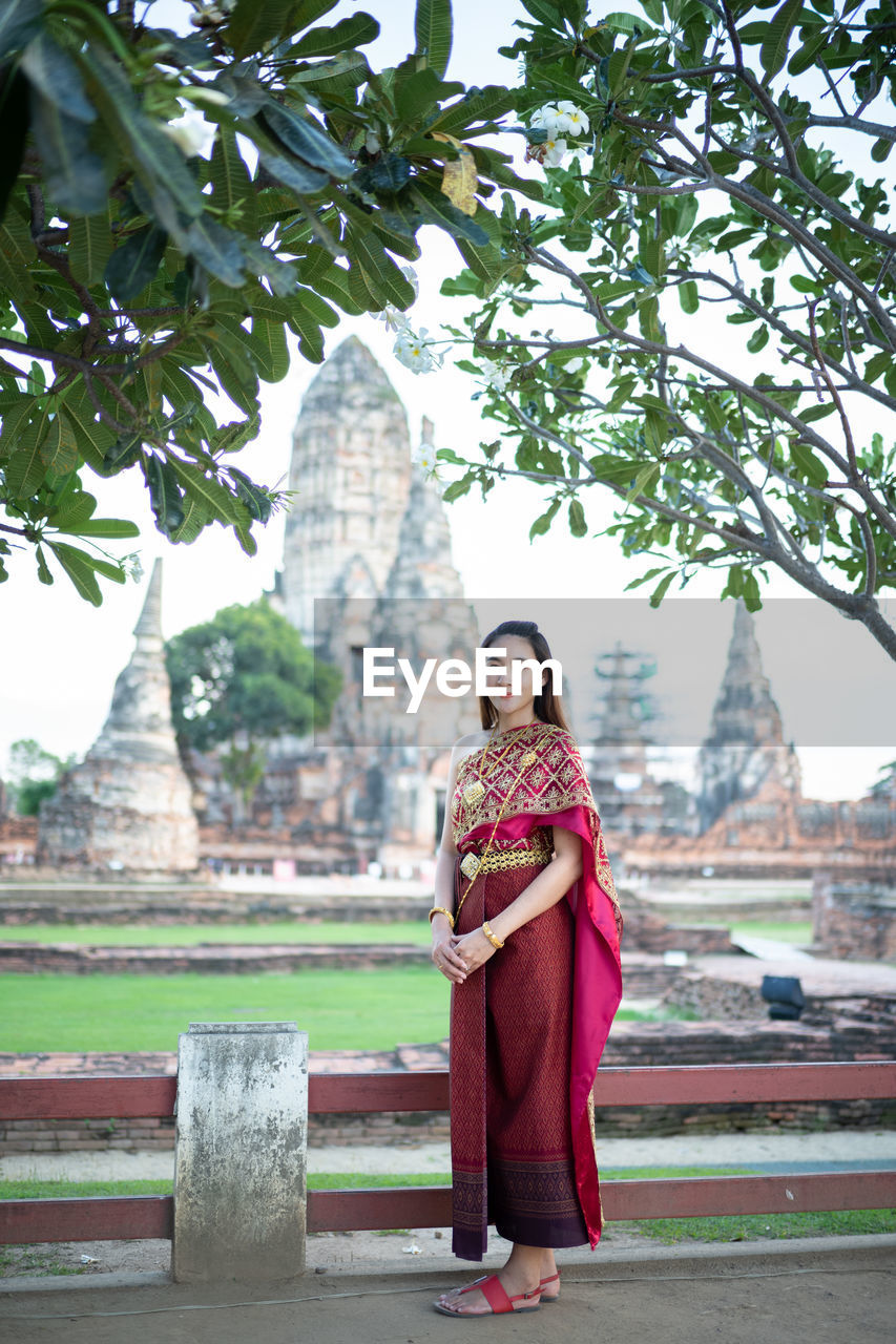 Portrait of woman standing in traditional clothing against temple