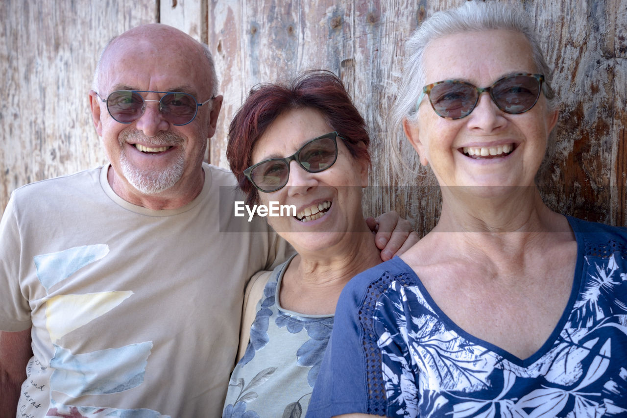 Portrait of smiling people standing by wall