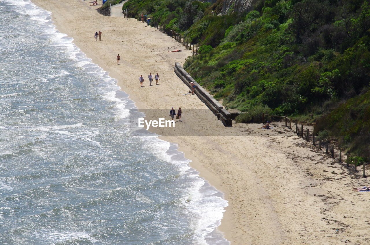 High angle view of people walking at beach during sunny day