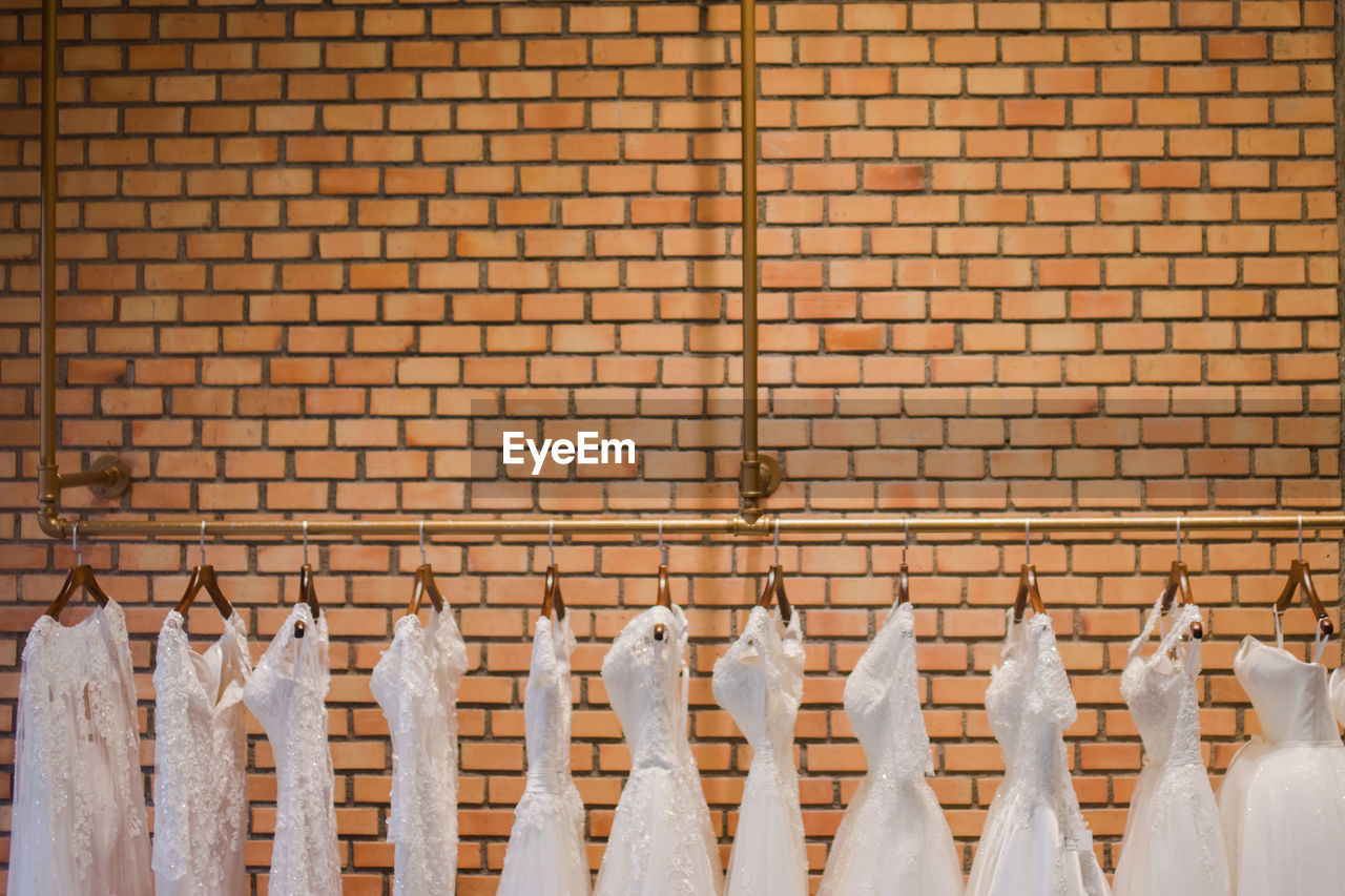 Dresses hanging against brick wall
