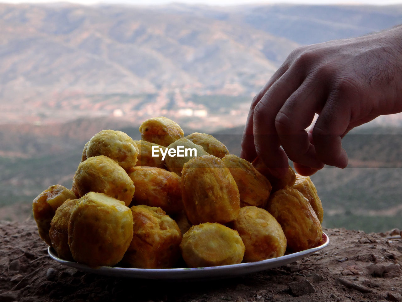 CLOSE-UP OF HAND HOLDING ICE CREAM IN MOUNTAINS