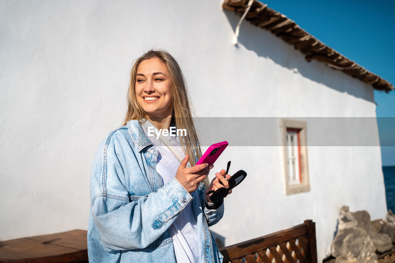 portrait of smiling young woman using mobile phone
