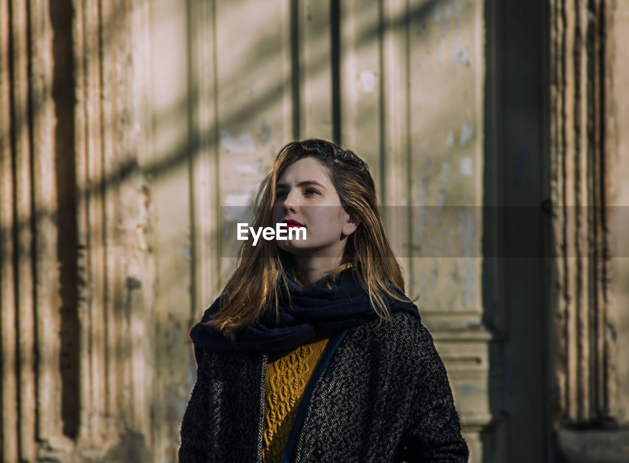 Young woman standing against wall