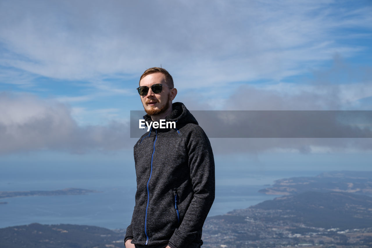 Man wearing sunglasses standing against sky