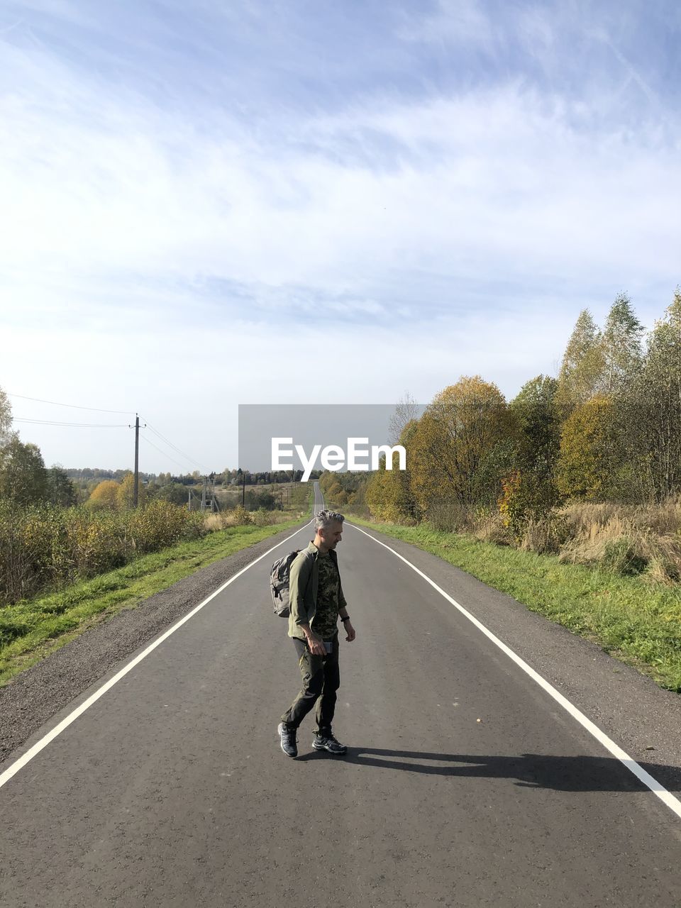 Rear view of man walking on road against sky