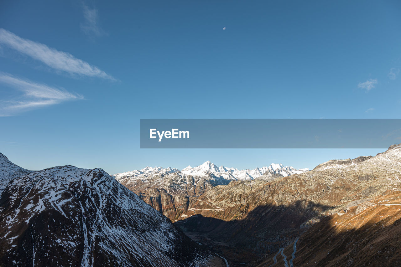 Scenic view of snowcapped mountains against blue sky