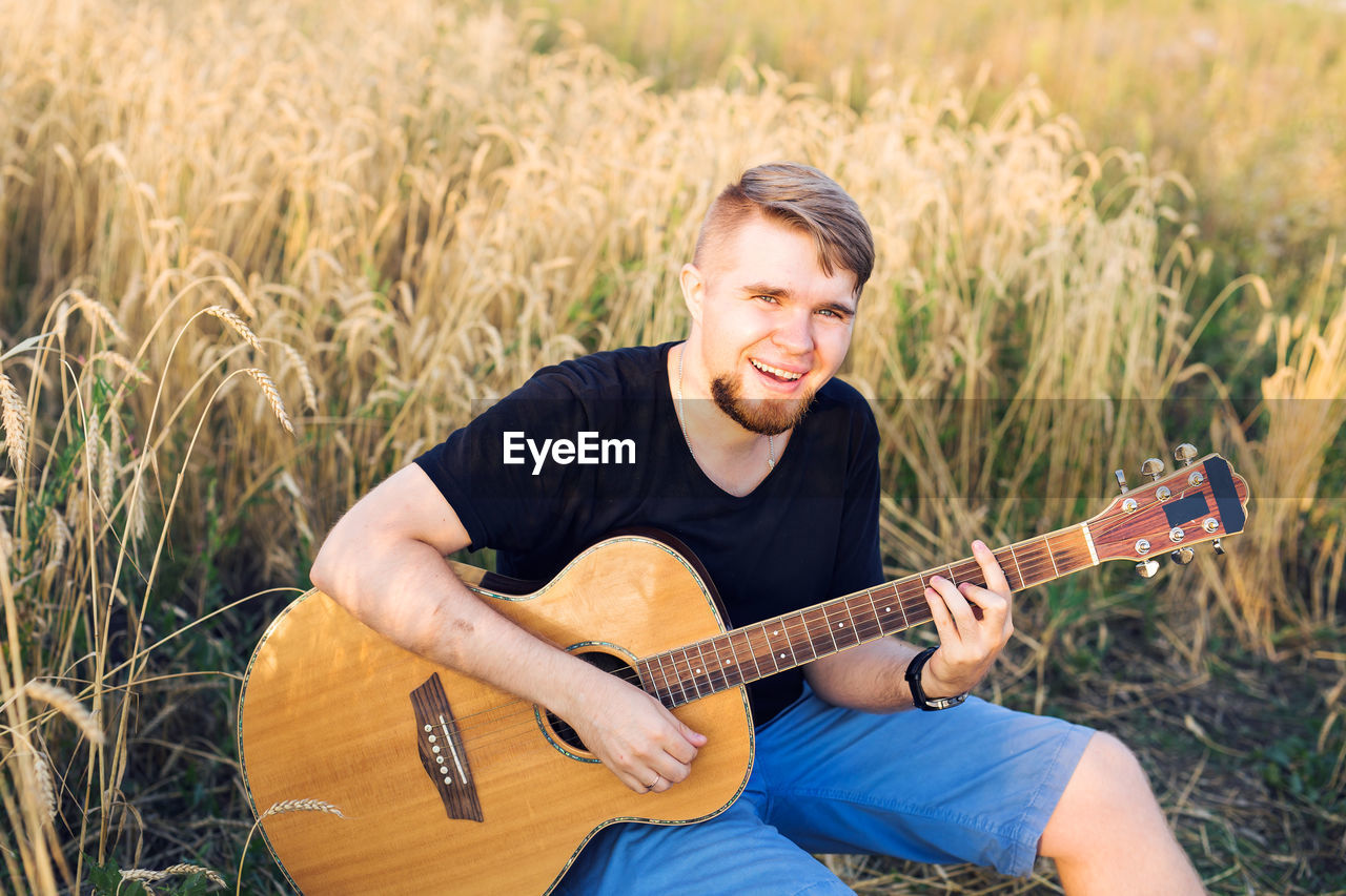 YOUNG MAN PLAYING GUITAR ON GRASS