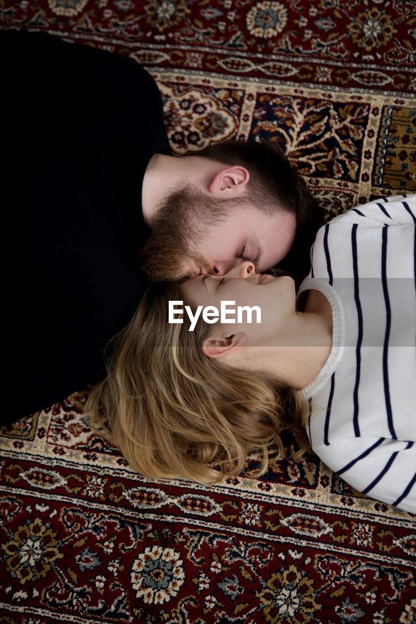High angle view of loving young couple lying on carpet
