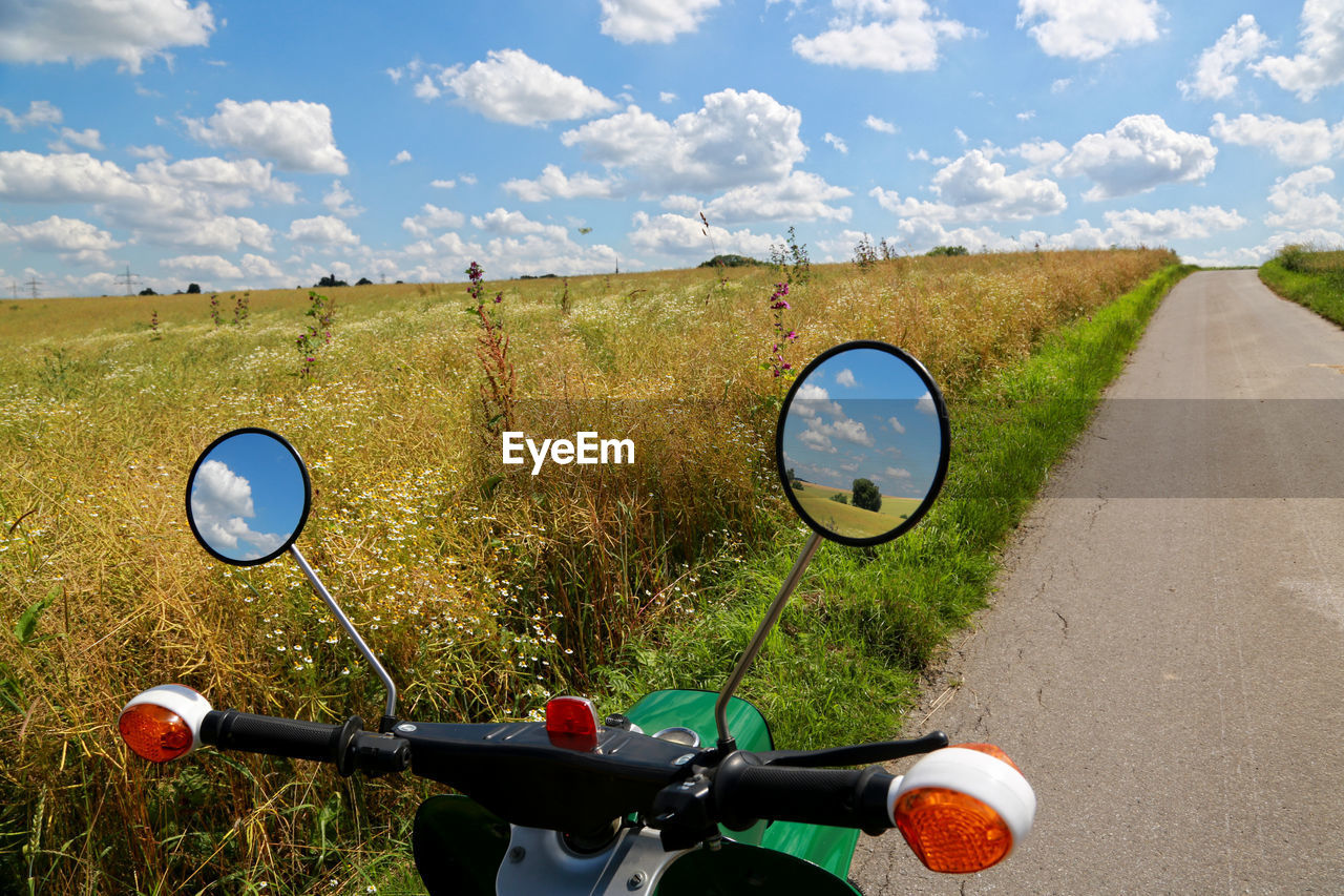 Eastern german bicycle parked on field by road against sky