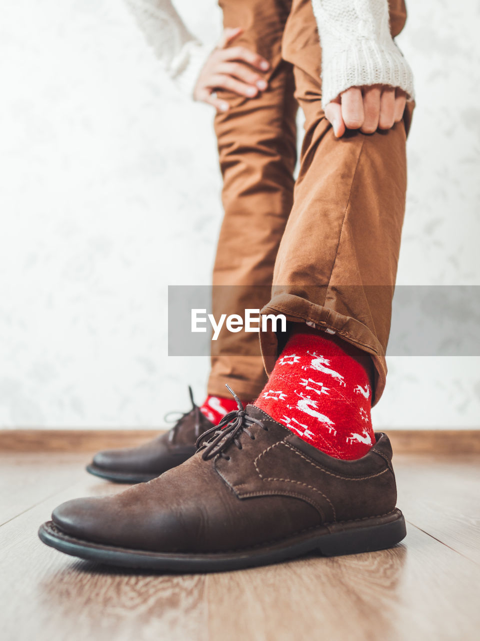 Young man shows red socks with reindeers on them. scandinavian pattern. new year and christmas.