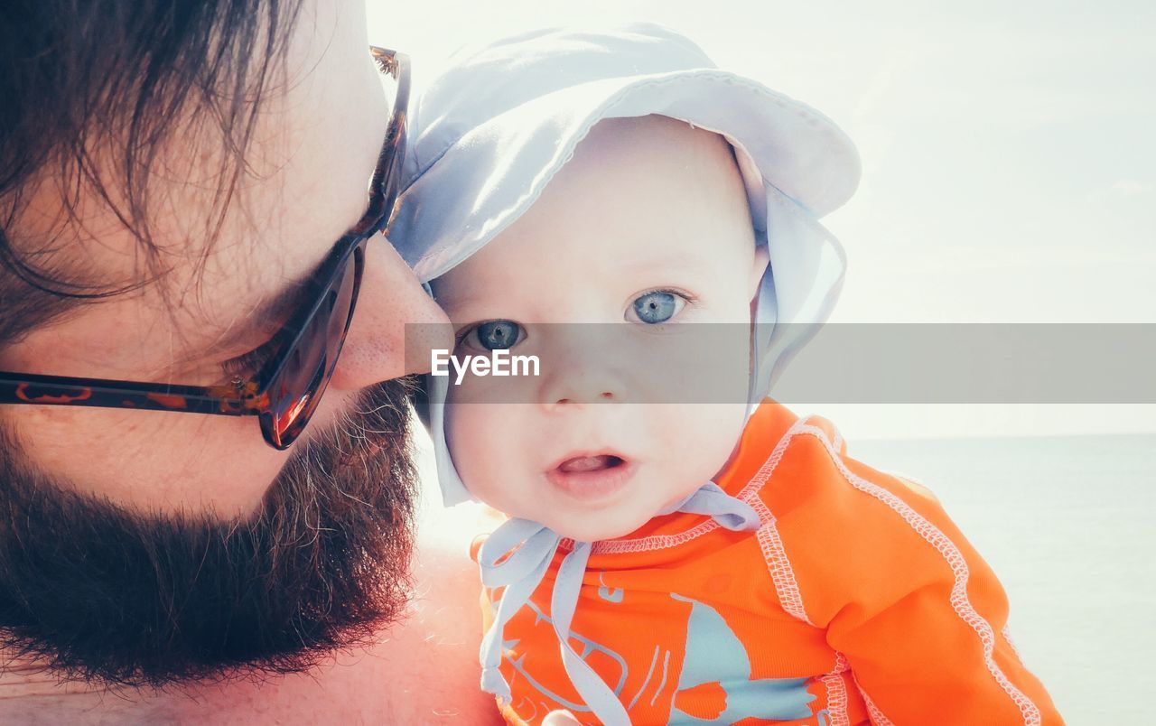 Close-up of mature man carrying son at beach