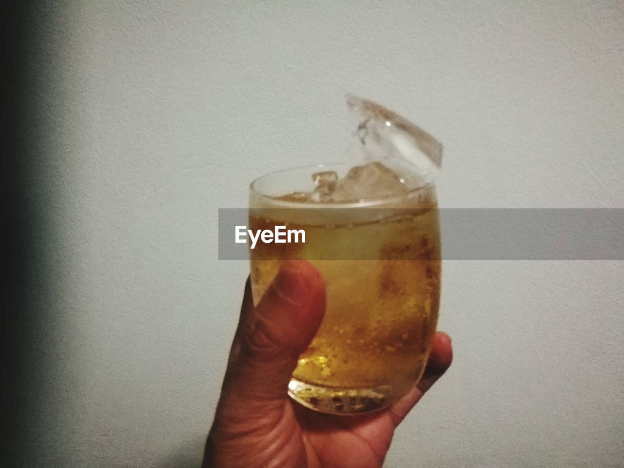 CLOSE-UP OF A HAND HOLDING GLASS OF DRINKING GLASSES