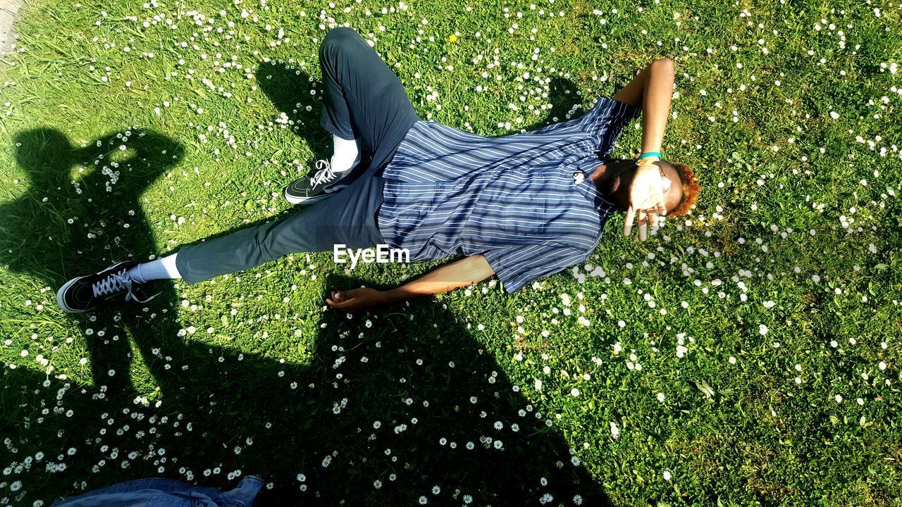 LOW SECTION OF MAN LYING DOWN GRASS