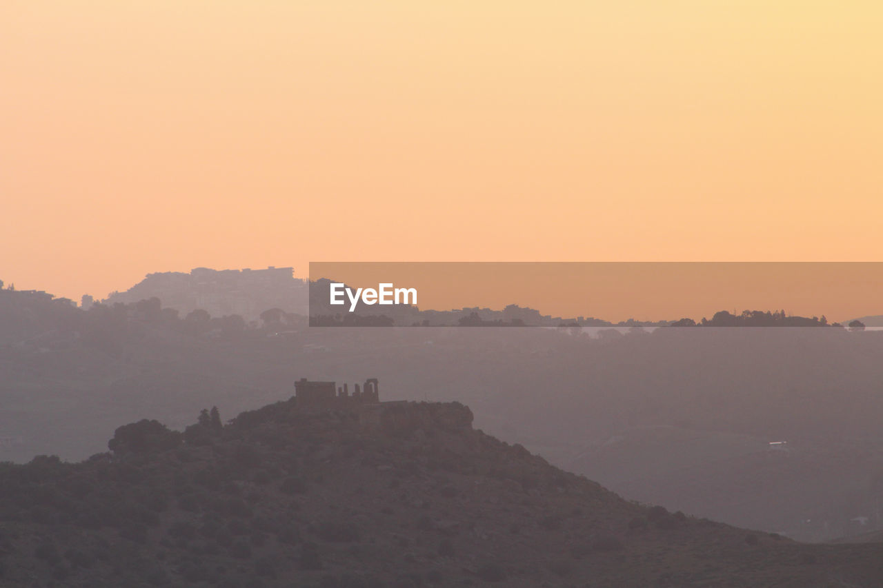 SILHOUETTE OF MOUNTAIN AGAINST SUNSET SKY