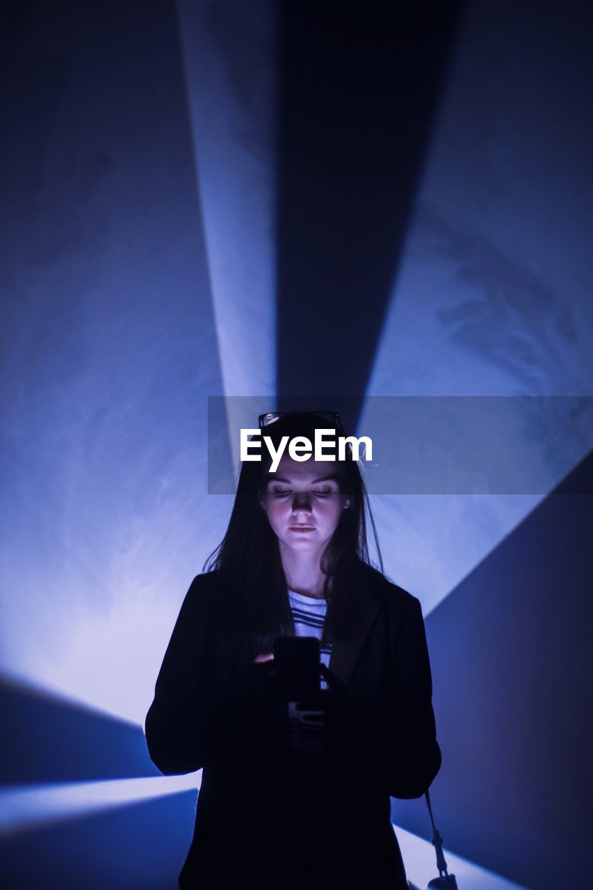 Young woman using smart phone while standing in tunnel