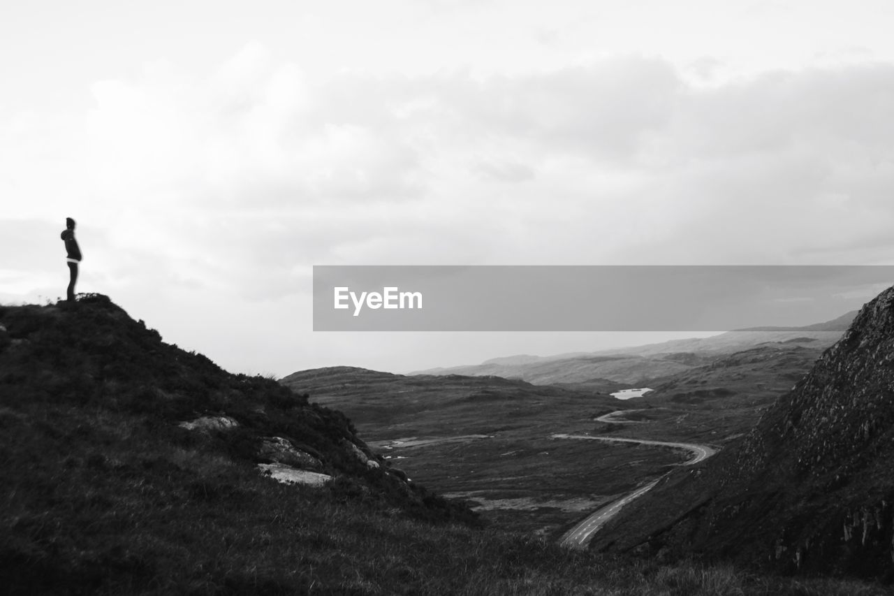 MAN STANDING ON MOUNTAIN