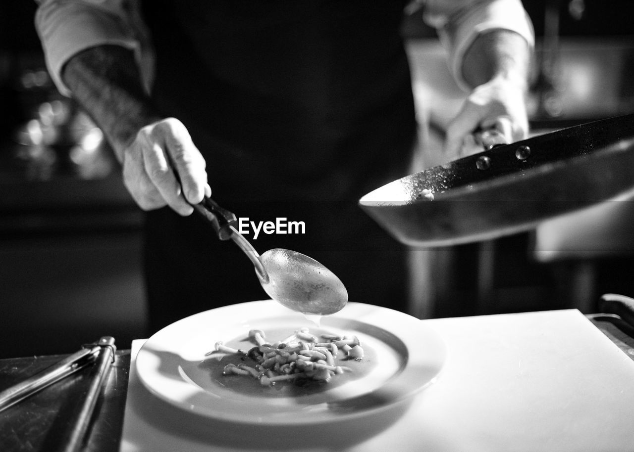 MIDSECTION OF PERSON PREPARING FOOD IN KITCHEN