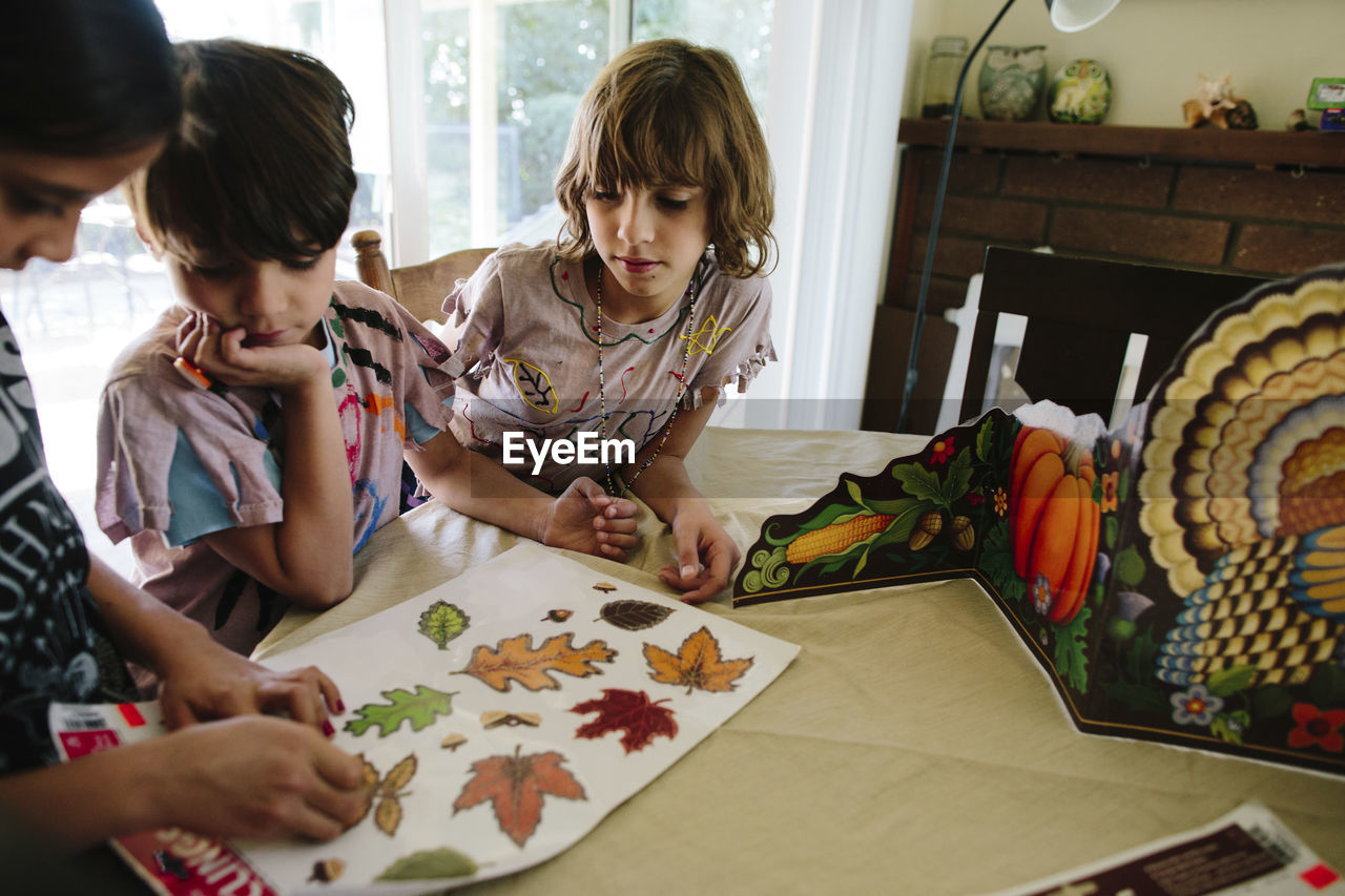 Girl with siblings removing leaves labels at table