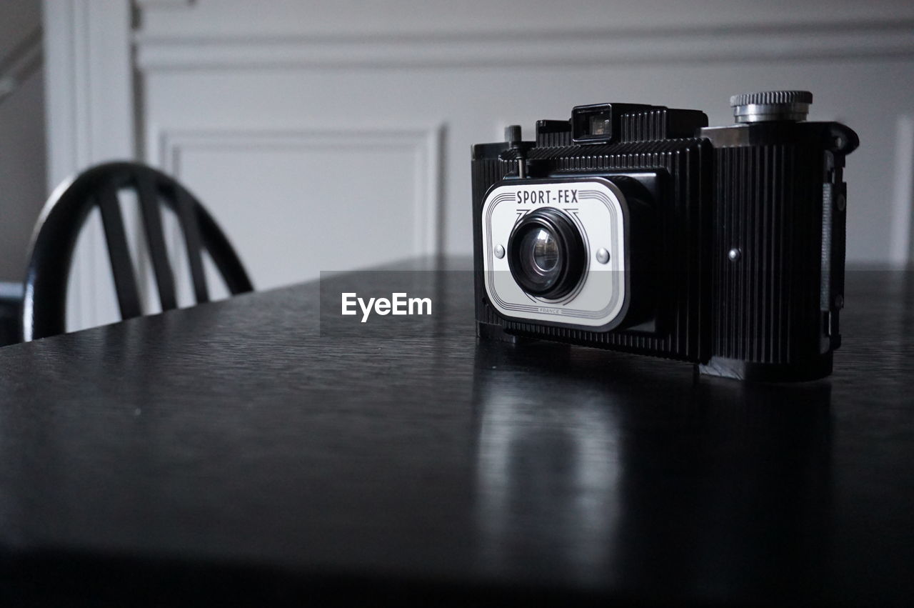 black, white, camera, technology, indoors, table, retro styled, lens - optical instrument, black and white, no people, digital slr, photographic equipment, monochrome, still life, selective focus, camera film, close-up