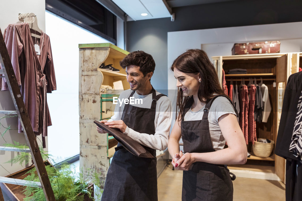 Smiling male and female colleagues checking folder while working in store