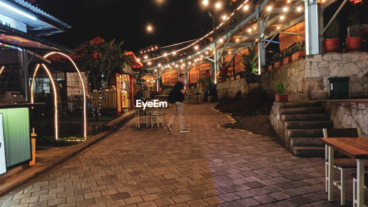 STREET AMIDST ILLUMINATED BUILDINGS AT NIGHT