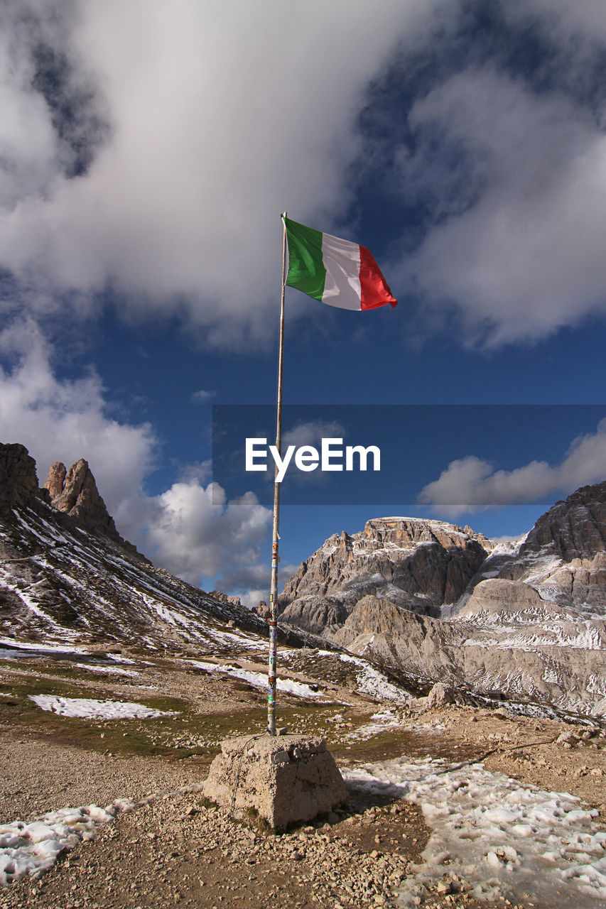 Low angle view of flag against mountain - dolomites mountains - locatelli refuge - italy