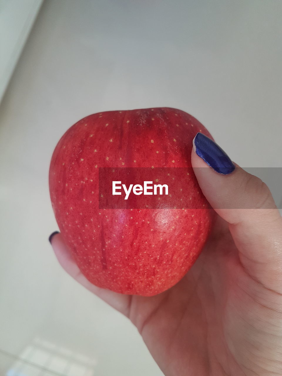 CLOSE-UP OF HAND HOLDING RED FRUIT