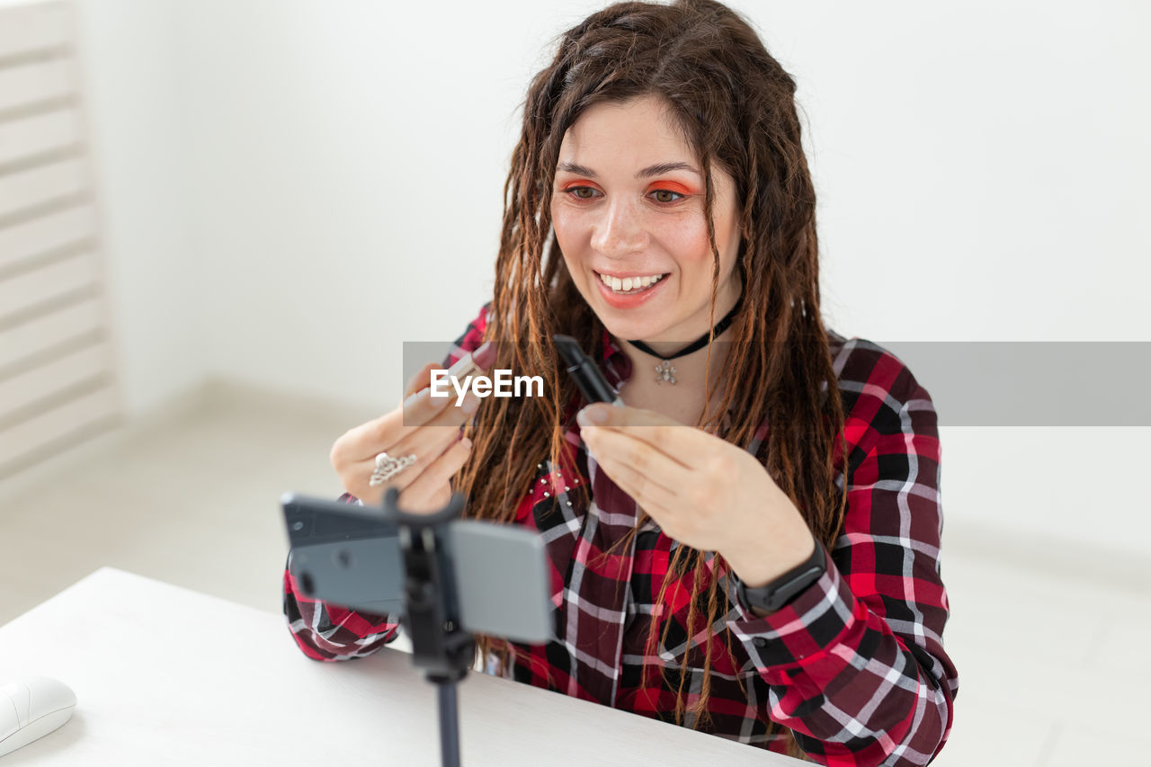 Portrait of smiling young woman holding camera