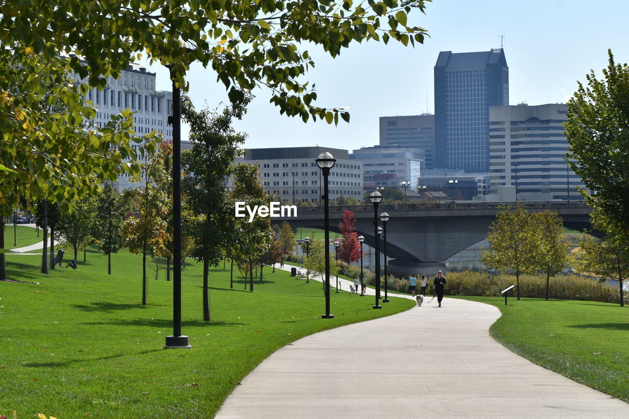 Footpath amidst trees in park against buildings in city. bicentennial park along scioto river