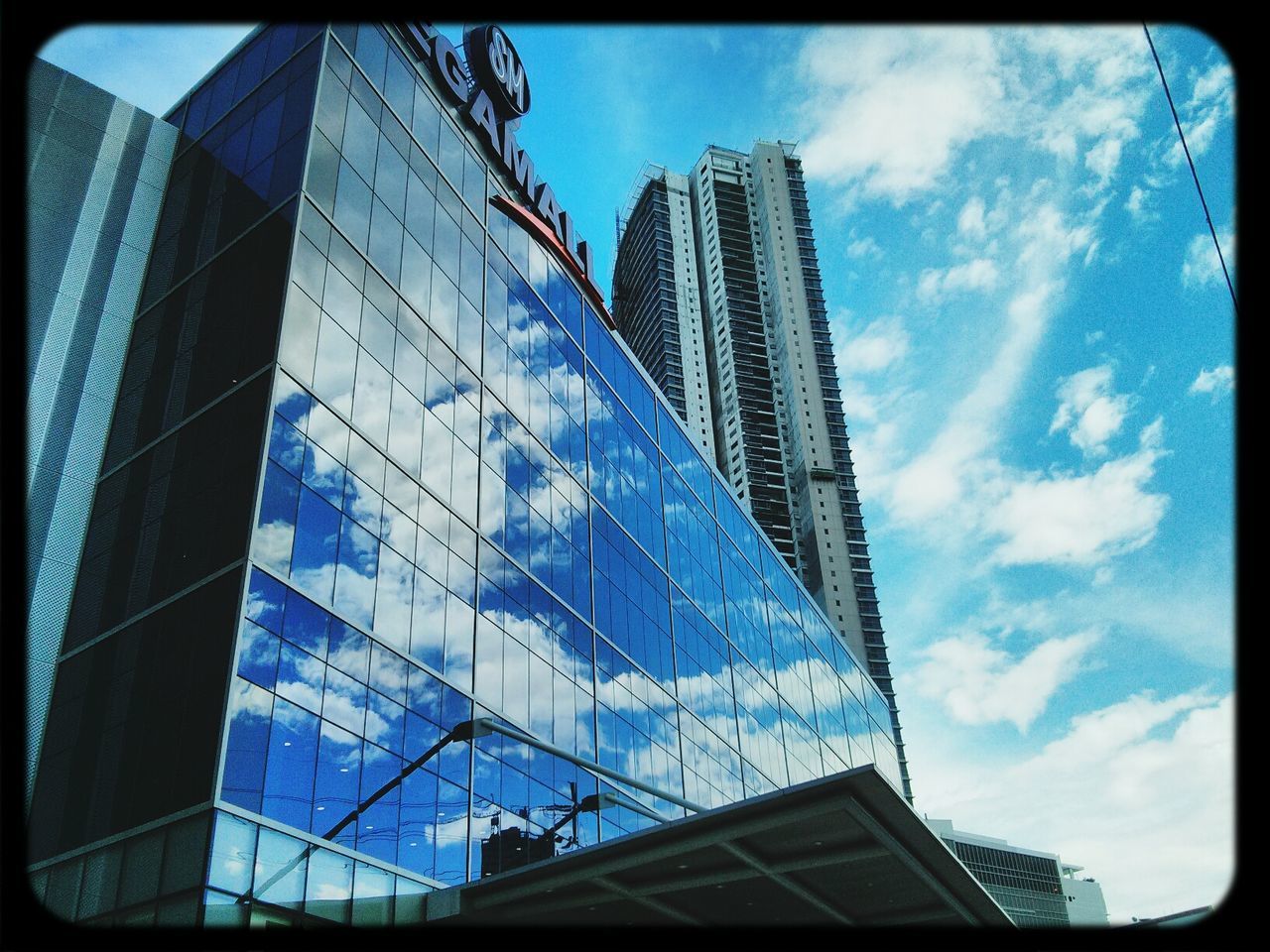 LOW ANGLE VIEW OF MODERN BUILDING AGAINST CLOUDY SKY
